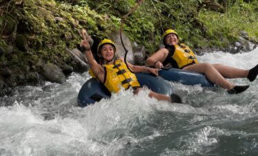 Young women doing extreme tubing through rapids in Rio Celeste