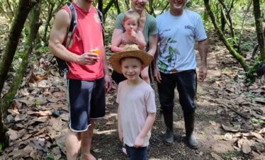 Young familiy with on the cacao farm with fresh cacao seeds