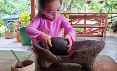 Child grinds cocoa the traditional way to make chocolate