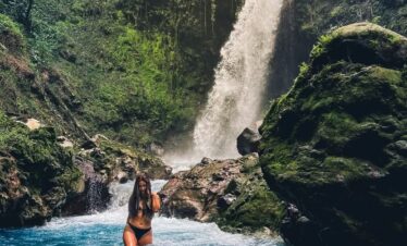Woman bathing in the waterfall Morpho Azul in Upala, Costa Rica